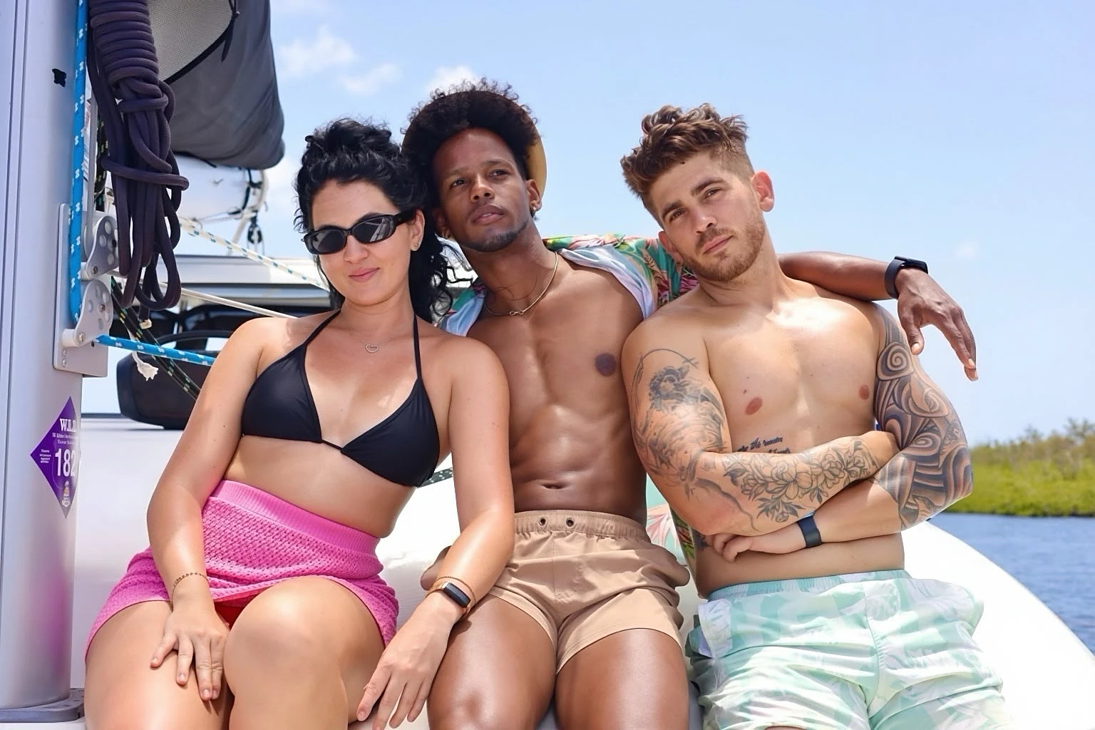 Three guests sitting together on the deck of a catamaran during the Blue Sky Sailing bachata boat