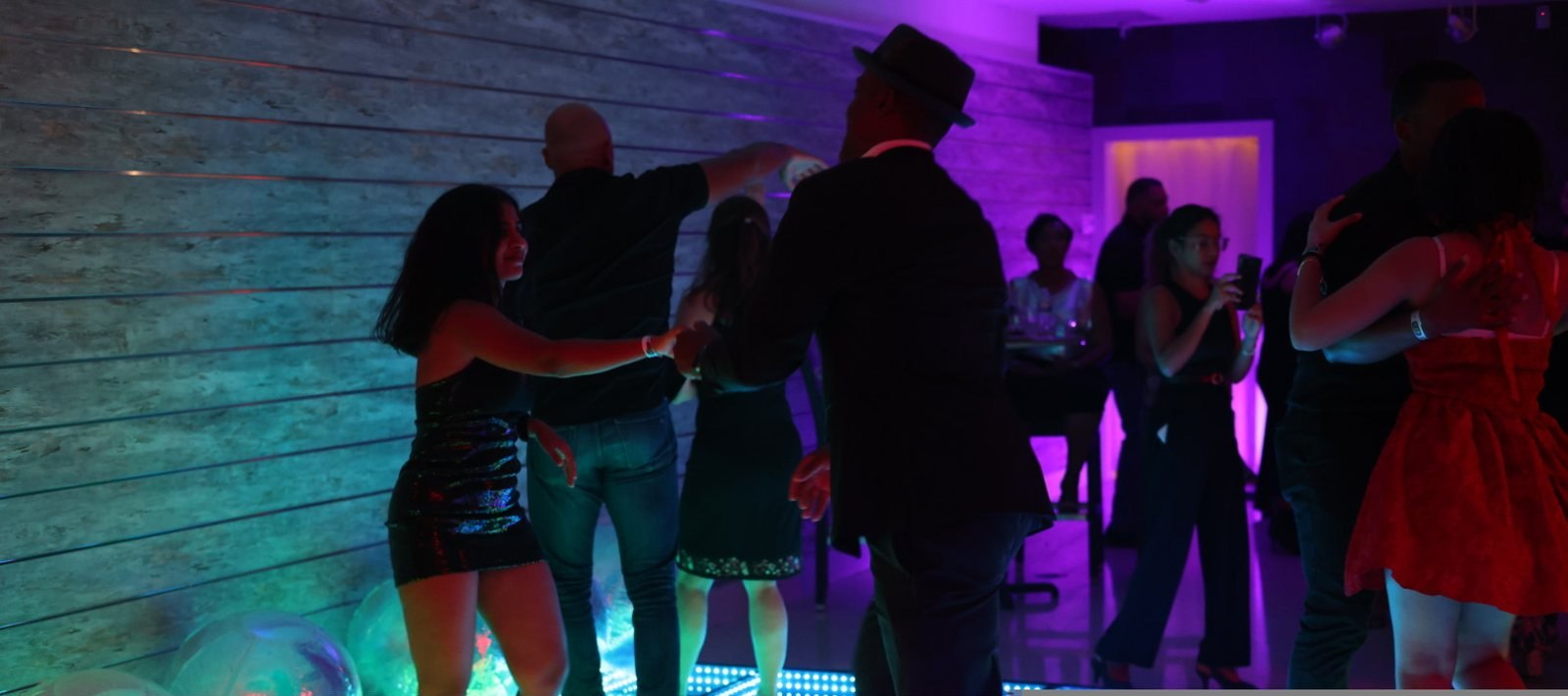 Guests sharing the social dance floor under colorful lights
