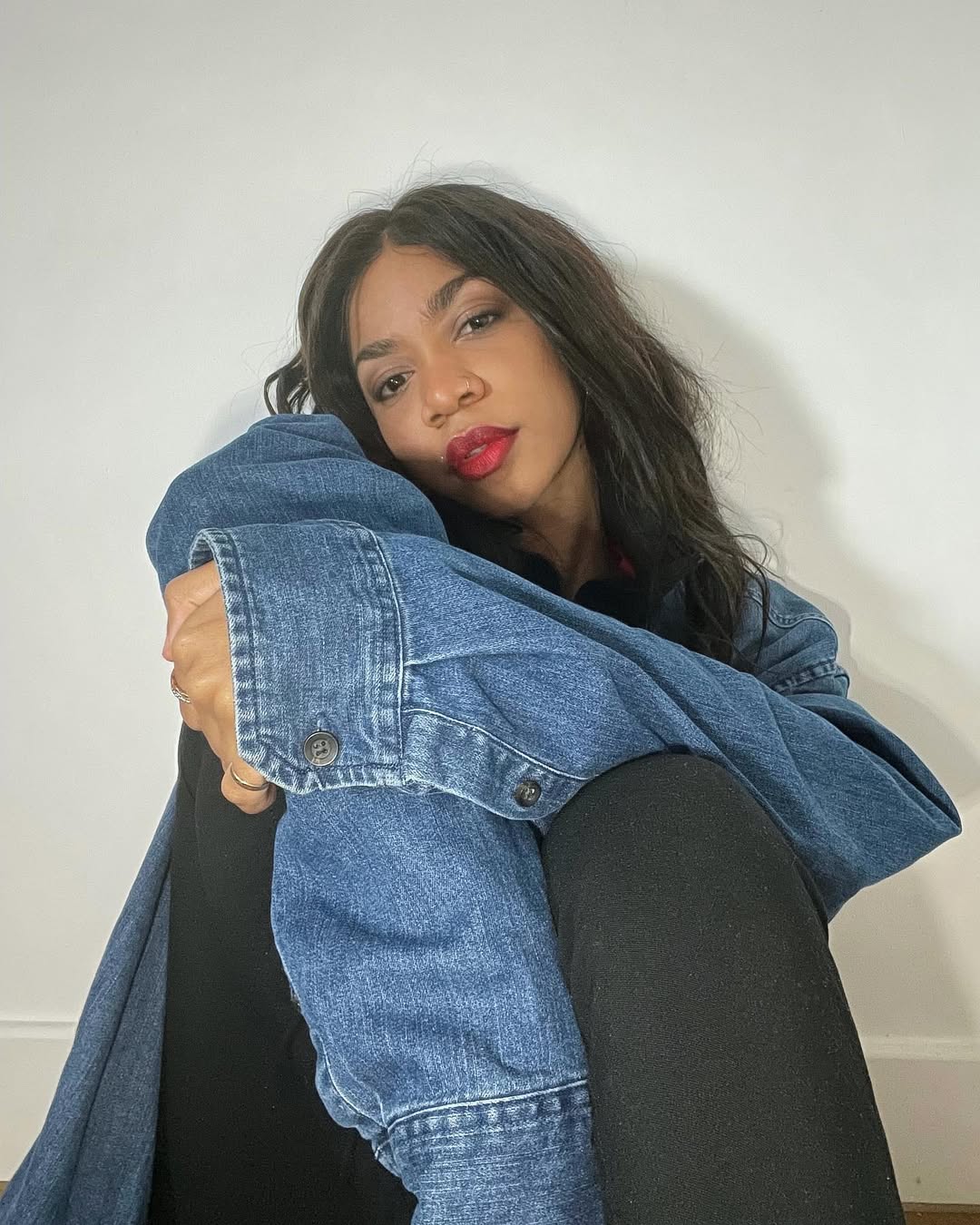 Jazz Jennings with brown hair, seated in a blue denim jacket against a light wall
