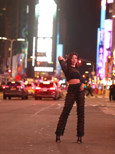 Jazz posing in a black outfit against city lights at night