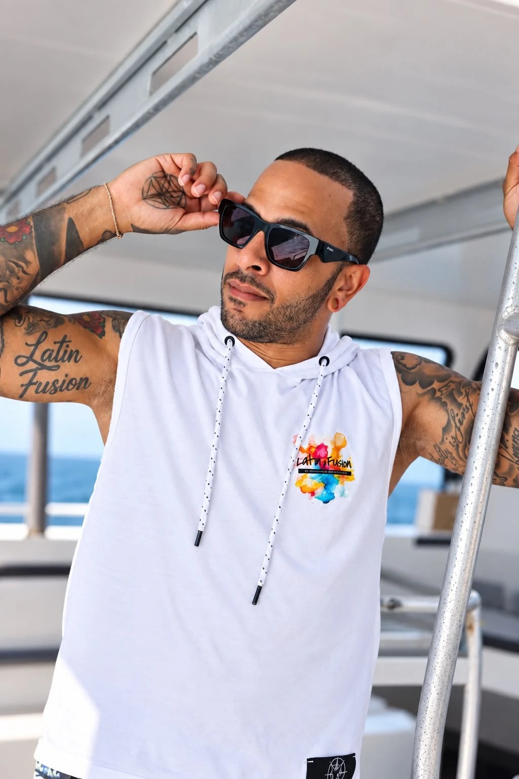 Model wearing the white Latin Fusion sleeveless hoodie with the watercolour logo on the chest