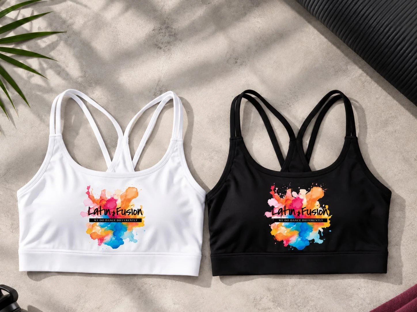 The Latin Fusion practice sports bra in white and in black, cross-back straps and the watercolour logo on the chest