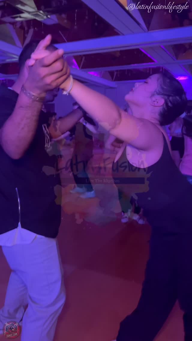 Two dancers sharing a close bachata connection under purple venue lights