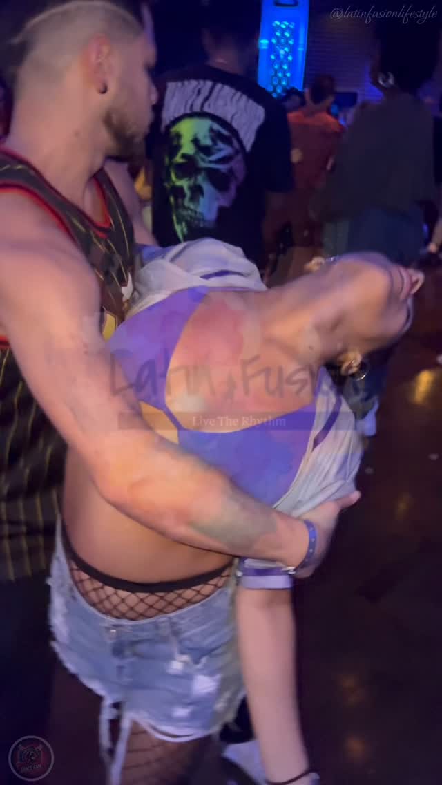 Two dancers moving together under blue and purple lights at a social